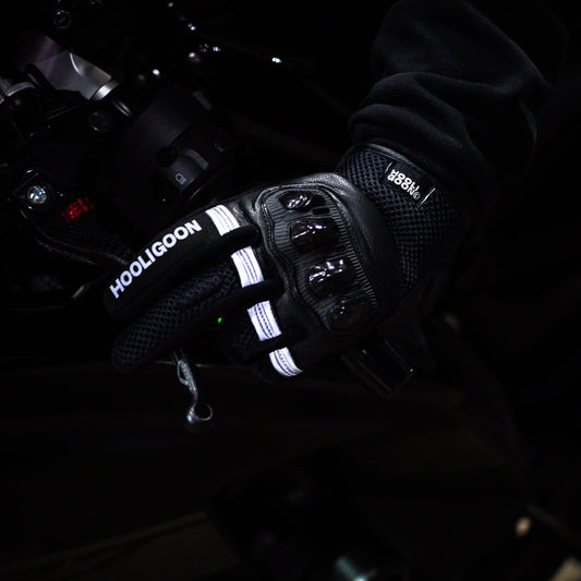 Close-up of gloved hands operating a vehicle's steering wheel with 'Hooligoon' branding.