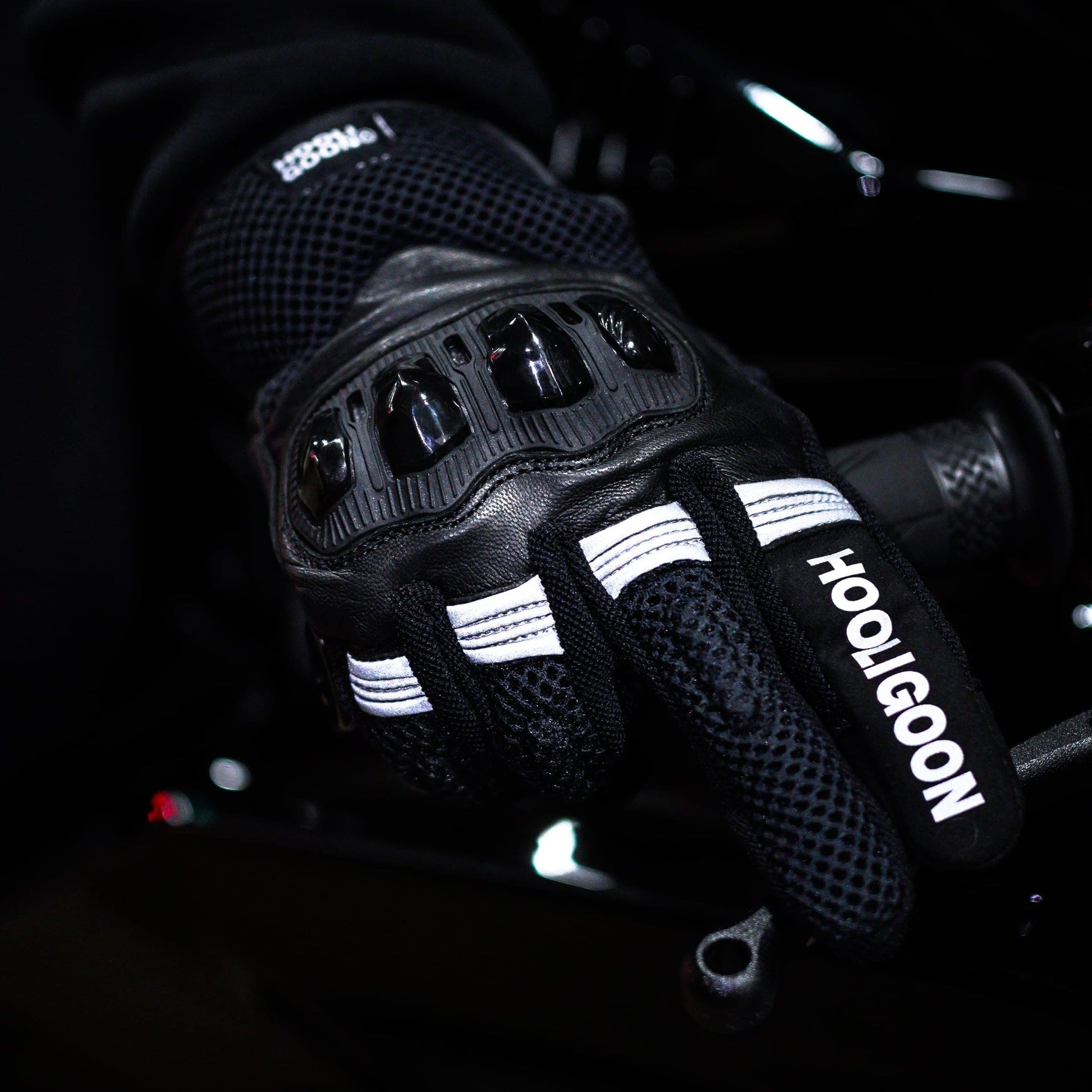 Black motorcycle glove with 'Hooligoon' branding on a dark background
