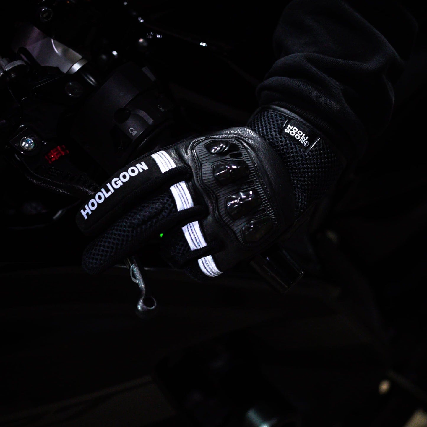 Close-up of gloved hands operating a vehicle's steering wheel with 'Hooligoon' branding.