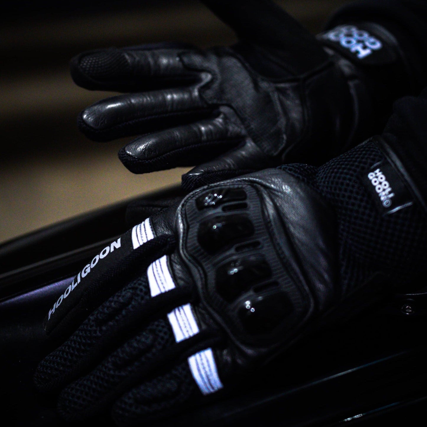Close-up of a gloved hand on a motorcycle handlebar with illuminated buttons.