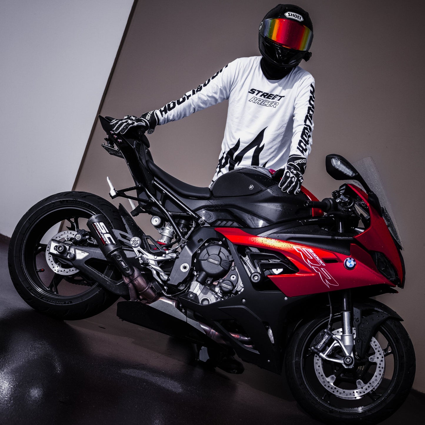 Person on a red motorcycle wearing a helmet and white jacket with black designs.